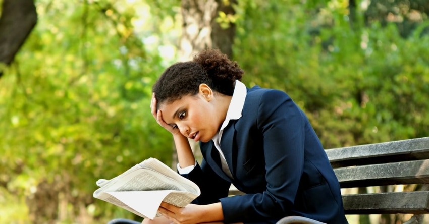 Woman on park bench holding newspaper is confused by latest bail bonding news