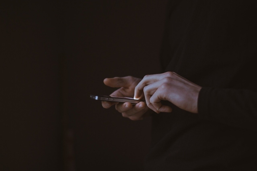 Employee in long-sleeved dark shirt dialing iphone to call and inform boss of recent arrest