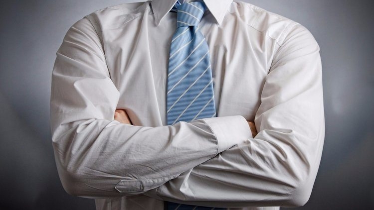 Employer in white collared shirt and tie crossing arms during discussion of employee's recent arrest